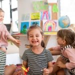 Small girl showing lost baby tooth indoors in classroom, looking at camera