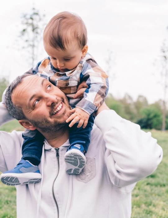 Dad playing son outdoor park riding piggyback