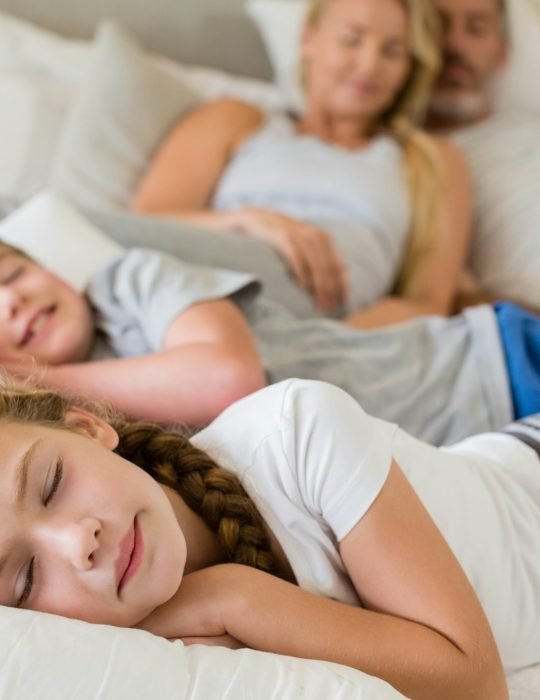 Parents and kids sleeping on bed in bedroom