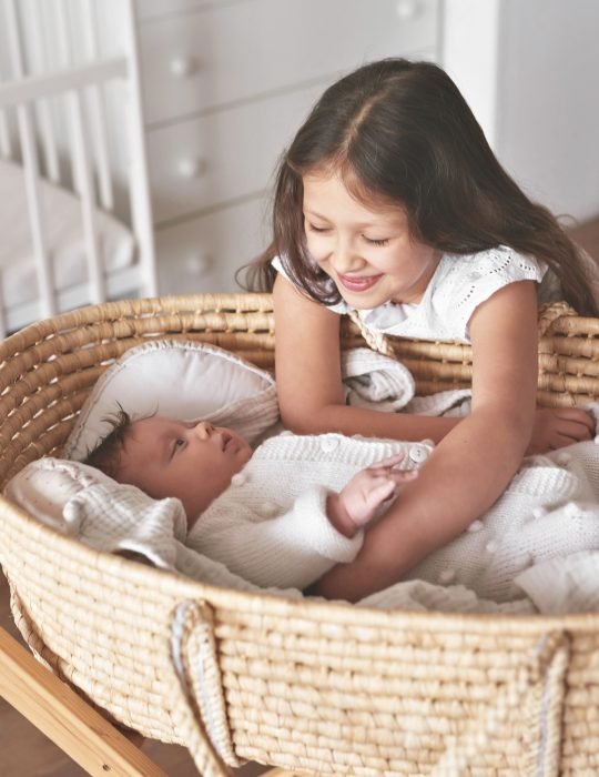 Sister and brother. Girl with baby boy in wicker cradle. Happy childhood. Children room